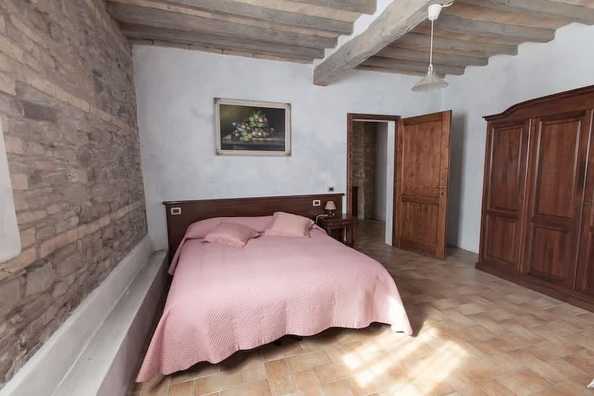 Camera dell'Agriturismo San Polo con travi in legno, pareti in pietra e letto matrimoniale a Castelvetro di Modena