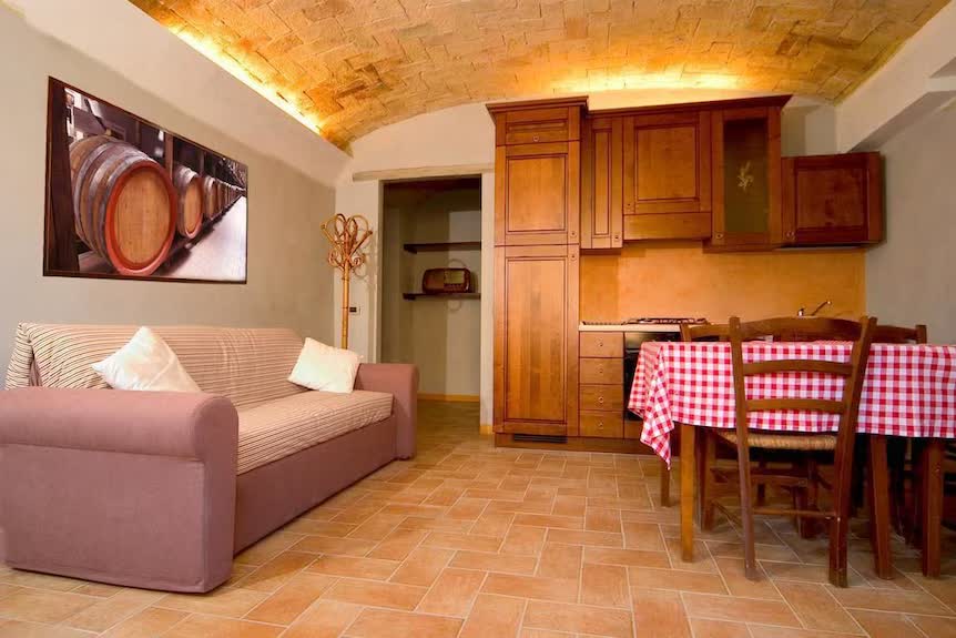 Soggiorno rustico dell'appartamento dell'Agriturismo San Polo con divano, cucina in legno e volta in mattoni