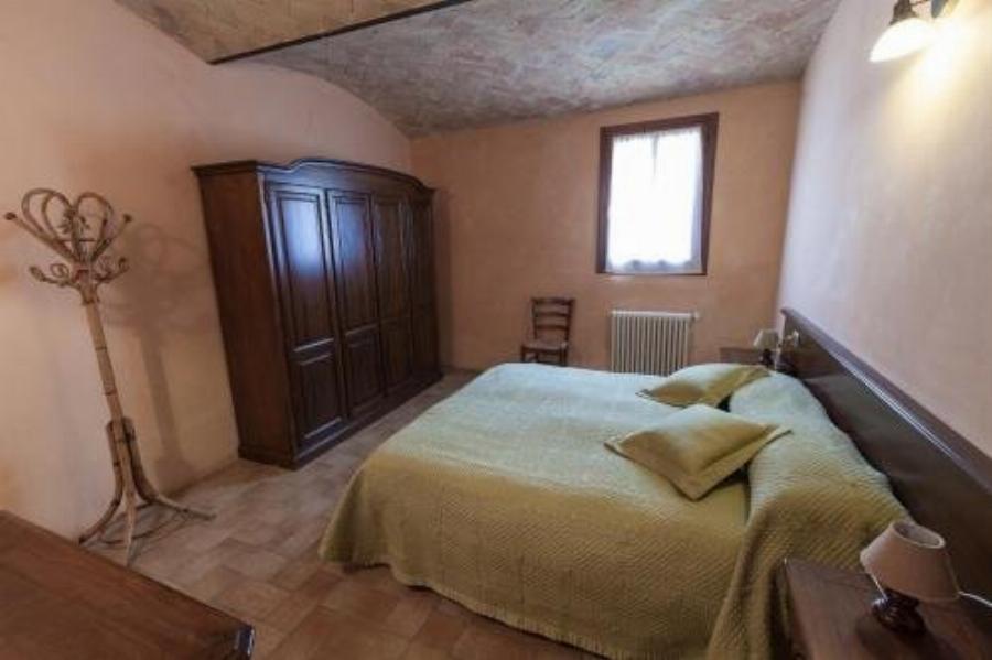 Camera matrimoniale con soffitto a volta in mattoni e copriletto verde all'Agriturismo San Polo di Castelvetro