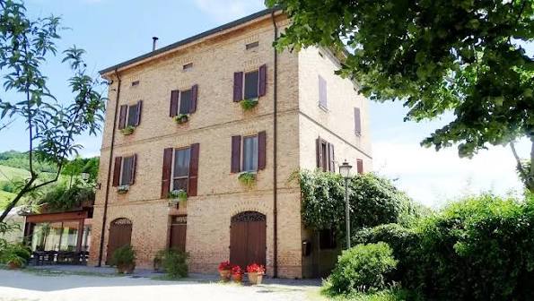 Facciata del casale storico dell'Agriturismo San Polo a Castelvetro di Modena tra il verde delle colline