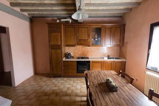 Cucina dell'appartamento dell'Agriturismo San Polo con travi in legno, cucina in legno e tavolo in stile country