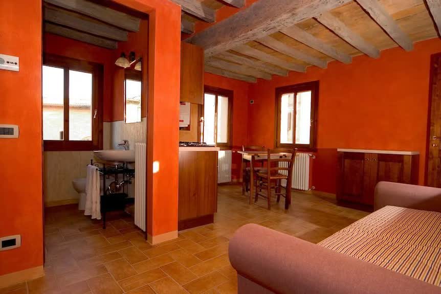 Appartamento dell'Agriturismo San Polo con pareti calde arancio, angolo cottura e zona pranzo tra le colline modenesi